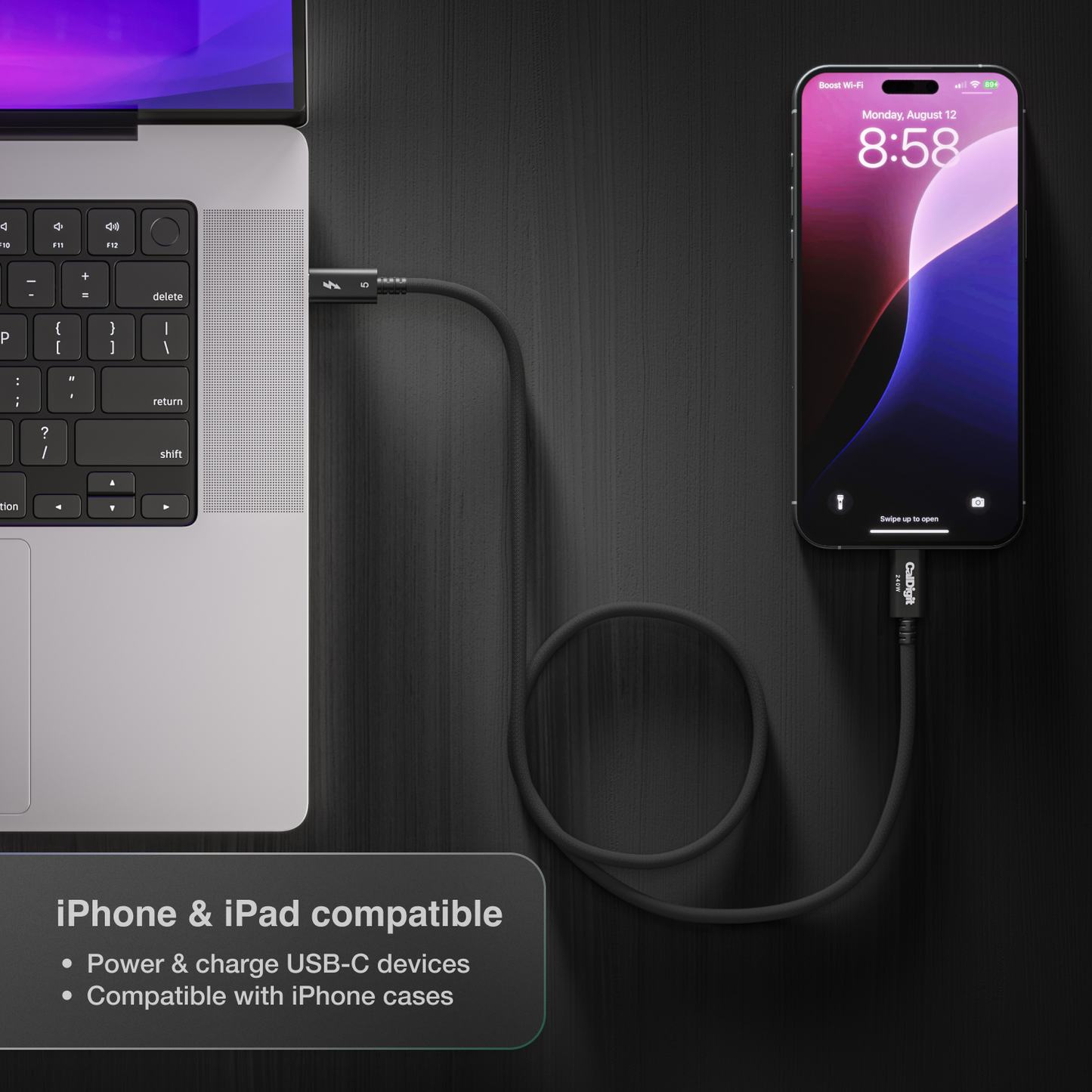 Laptop and smartphone connected by a cable on a dark surface