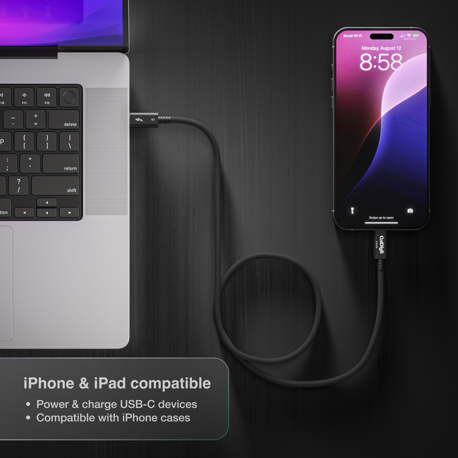 Laptop and smartphone connected by a cable on a dark surface