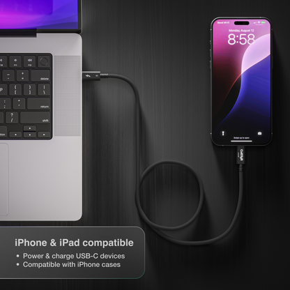 Laptop and smartphone connected by a cable on a dark surface